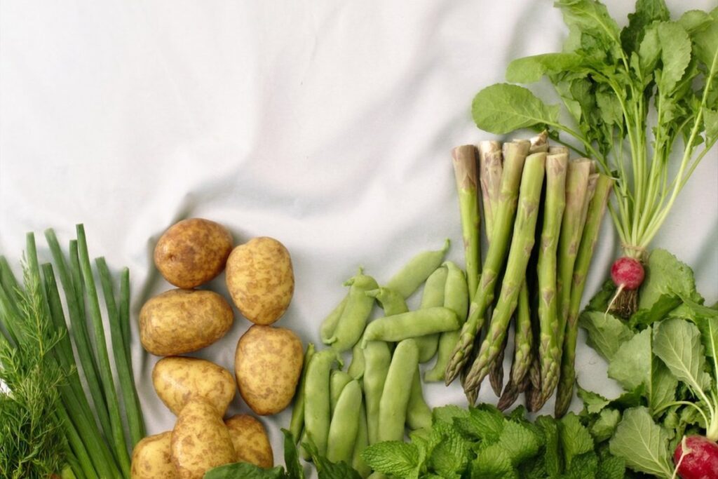 New Zealand spring produce laid out on linen: asparagus, new potatoes, broad beans, radishes and spring onions